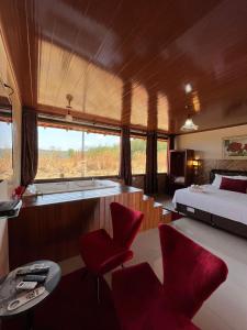 a bedroom with a bed and red chairs and a table at Pousada Encanto dos Anjos in Pirenópolis