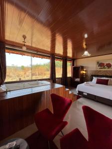 a bedroom with a bed and a window and red chairs at Pousada Encanto dos Anjos in Pirenópolis