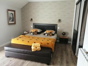 a bedroom with a large bed with a yellow comforter at Le Douétaux chambres d'hotes in La Baussaine