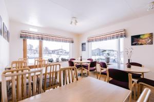 a dining room with tables and chairs and windows at Eldá Guesthouse in Myvatn