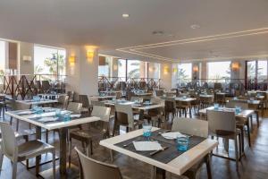 un ristorante con tavoli, sedie e finestre di Estudio El Balcón, en primerísima línea de playa. a Fuengirola