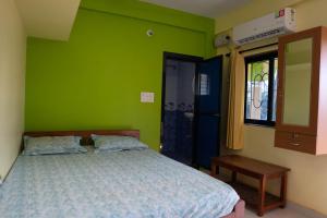 a bedroom with a bed with a green wall at Dhanashree Riverview Hotel in Corgao