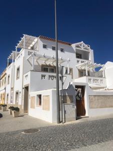 ein weißes Gebäude mit einer Stange davor in der Unterkunft Guarda Rios in Vila Nova de Milfontes