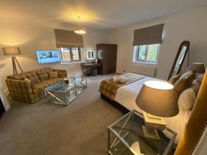 a bedroom with a bed and a couch and a table at Ashorne Hill Leamington Spa in Leamington Spa