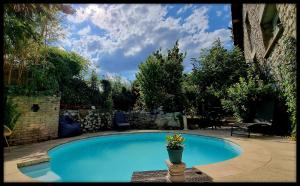 niebieski basen z doniczką obok niego w obiekcie Lion-Les Jardins de Kuz w mieście Bernin