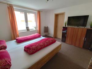 Schlafzimmer mit einem Bett mit roter Bettwäsche und einem Flachbild-TV in der Unterkunft Ferienwohnung Cassiopeia in Harzgerode