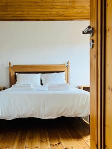 un letto con lenzuola e cuscini bianchi in una camera da letto di Casa do Rio Alva ad Arganil