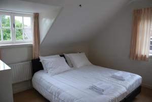 una camera da letto con letto, lenzuola e cuscini bianchi di Vakantiehuis De Vorster Pastorie a Broekhuizenvorst