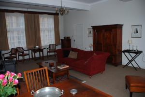 a living room with a red couch and a table at Vakantiehuis De Vorster Pastorie in Broekhuizenvorst