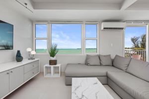 a white living room with a couch and a tv at Amapola SeaSide Beach Front Apartment in San Juan