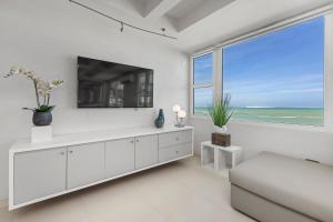 - un salon blanc avec une télévision et un canapé dans l'établissement Amapola SeaSide Beach Front Apartment, à San Juan