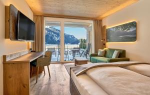 a hotel room with a bed and a desk and a television at haldensee - Naturerlebnis und Wellnesshotel in Nesselwängle