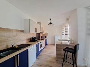 kuchnia z niebiesko-białymi szafkami i stołkiem w obiekcie Belle Maison MALOU climatisée calme, piscine, jacuzzi 3km plage Labenne Capbreton w mieście Labenne