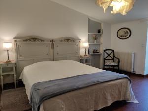 Un dormitorio con una gran cama blanca y una lámpara de araña. en Chateau Ysard, en Camblanes-et-Meynac
