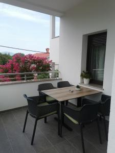una mesa y sillas en un balcón con ventana en Apartmani Nika, en Rijeka