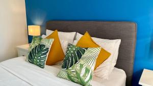 Una cama con almohadas amarillas y verdes. en Oneluxstay Antwerp City Centre en Amberes