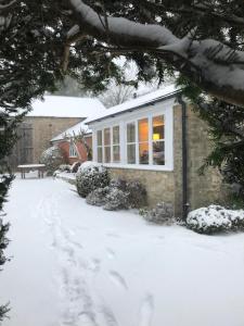 una casa nella neve con un vialetto coperto di neve di Norburton Hall Cottages a Bridport