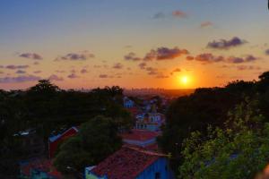 una puesta de sol sobre una ciudad con árboles y edificios en Estúdio dos sonhos com bela vista próximo ao alto da sé, en Olinda 2 fotos más