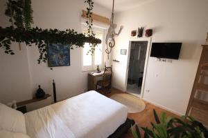 1 dormitorio con 1 cama blanca y TV en Il Chiostro, en Cagliari