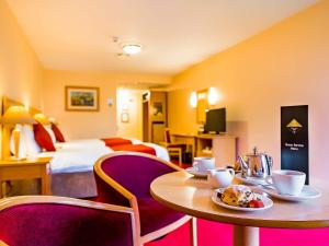 a hotel room with a table and chairs and a bed at Great National South Court Hotel in Limerick