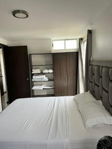1 dormitorio con 1 cama blanca grande y algunas toallas en Valle del lili cozy apartment, en Cali