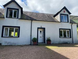 Casa blanca con 2 ventanas y una puerta en Exclusive private estate cottage en Lochearnhead