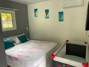 um pequeno quarto com uma cama e uma janela em Villas smoothie SYCARO em Le François