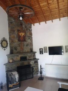 a living room with a stone fireplace and a ceiling fan at Veranda in Agros