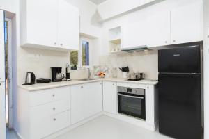 a kitchen with white cabinets and a black refrigerator at Blue Violet Apartment in Drios