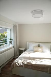 a white bedroom with a bed and a window at Ferienhus #1 Nordfriesland in Mildstedt