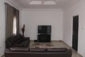 Una sala de estar con un sofá y un televisor de pantalla plana. en Koring Residence at Dalaba Estate, en Jarbang