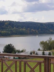vistas a un lago con un barco en el agua en Domki Na Wzgórzu Słońce JACUZZI SAUNA ROWERY, en Zawóz