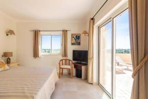 1 dormitorio con cama, TV y balcón en Villa Meijer Gramacho Golf, en Estômbar