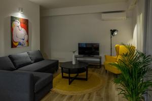 ein Wohnzimmer mit einem Sofa, einem Tisch und einem TV in der Unterkunft Alyvia Central Apartment 1 in Ioannina