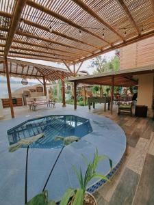a large swimming pool under a wooden pergola at Spondylus Lodge in Ayampe