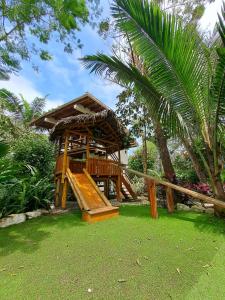 a wooden gazebo with a slide in a yard at Spondylus Lodge in Ayampe