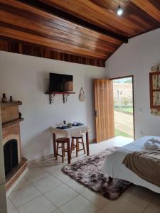 a bedroom with a bed and a table and a fireplace at Estalagem Do Luar in Monte Verde