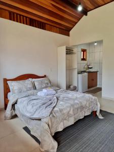 a large bed in a bedroom with a kitchen at Estalagem Do Luar in Monte Verde