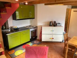 małą kuchnię z zielonymi szafkami i stołem w obiekcie Rustico a Roveredo GR w mieście Roveredo