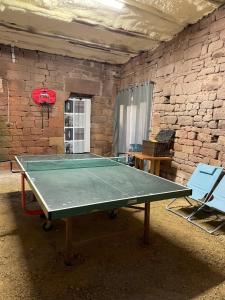 eine Tischtennisplatte in einem Zimmer mit Ziegelwand in der Unterkunft Villa avec jaccuzi in Noailhac