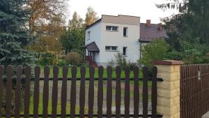 una valla de madera frente a una casa blanca en Apartament Tarnów-Mościce PRZY MOŚCIE en Tarnów