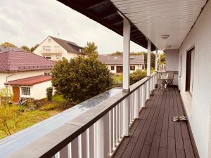 - une terrasse couverte avec des balustrades blanches et une vue sur une maison dans l'établissement Big apartment with Wood-Burning Stove & Balcony, à Butzbach