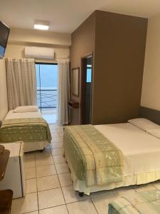 two beds in a bedroom with a view of the ocean at Marge Hotel in Aparecida