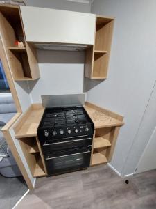 a kitchen with a black stove in a cabinet at KEE Holiday Home Caravan in Great Yarmouth