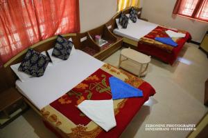 een kamer met 2 bedden en een stoel bij Sri Krishna residency in Ooty