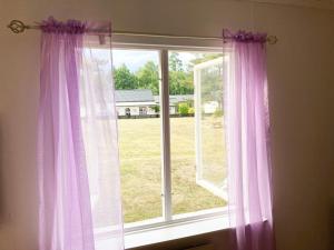 una ventana con cortinas moradas y vistas a un patio en Villa with 4 bed rooms with internet in Vimmerby en Gullringen