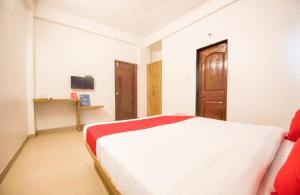 a bedroom with a white bed and a wooden door at Primrose Guest House in Pune