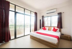 a bedroom with a bed with red pillows and a large window at Primrose Guest House in Pune