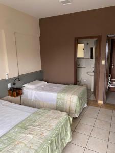 a hotel room with two beds and a bathroom at Marge Hotel in Aparecida