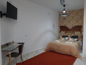 a bedroom with a bed and a desk and a television at Santa Marta in Martos +5 photos